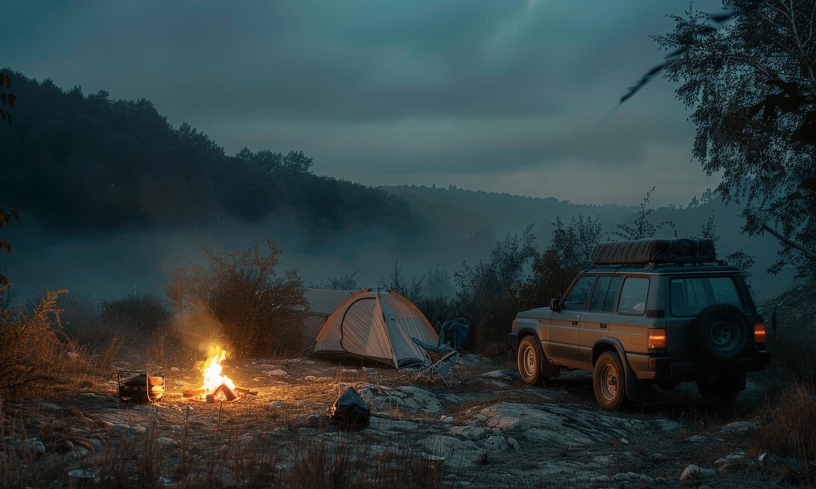 A KAJU camp at dusk with a campfire, tent and an overland 4x4 with a roof rack